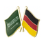 A friendship pin badge featuring enamel pins with the flags of Saudi Arabia and Germany, attached to a brass-plated iron base.