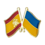 A pin badge featuring the flags of Spain and Ukraine with a yellow and blue color scheme, and a crown emblem on the Spanish flag.