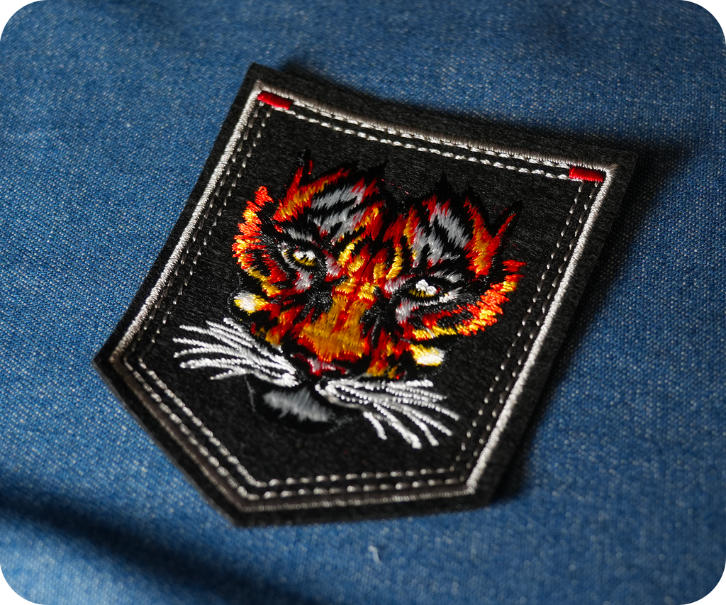 Tiger Face On Black Shield Iron On Patch (9 x 7.6cm)