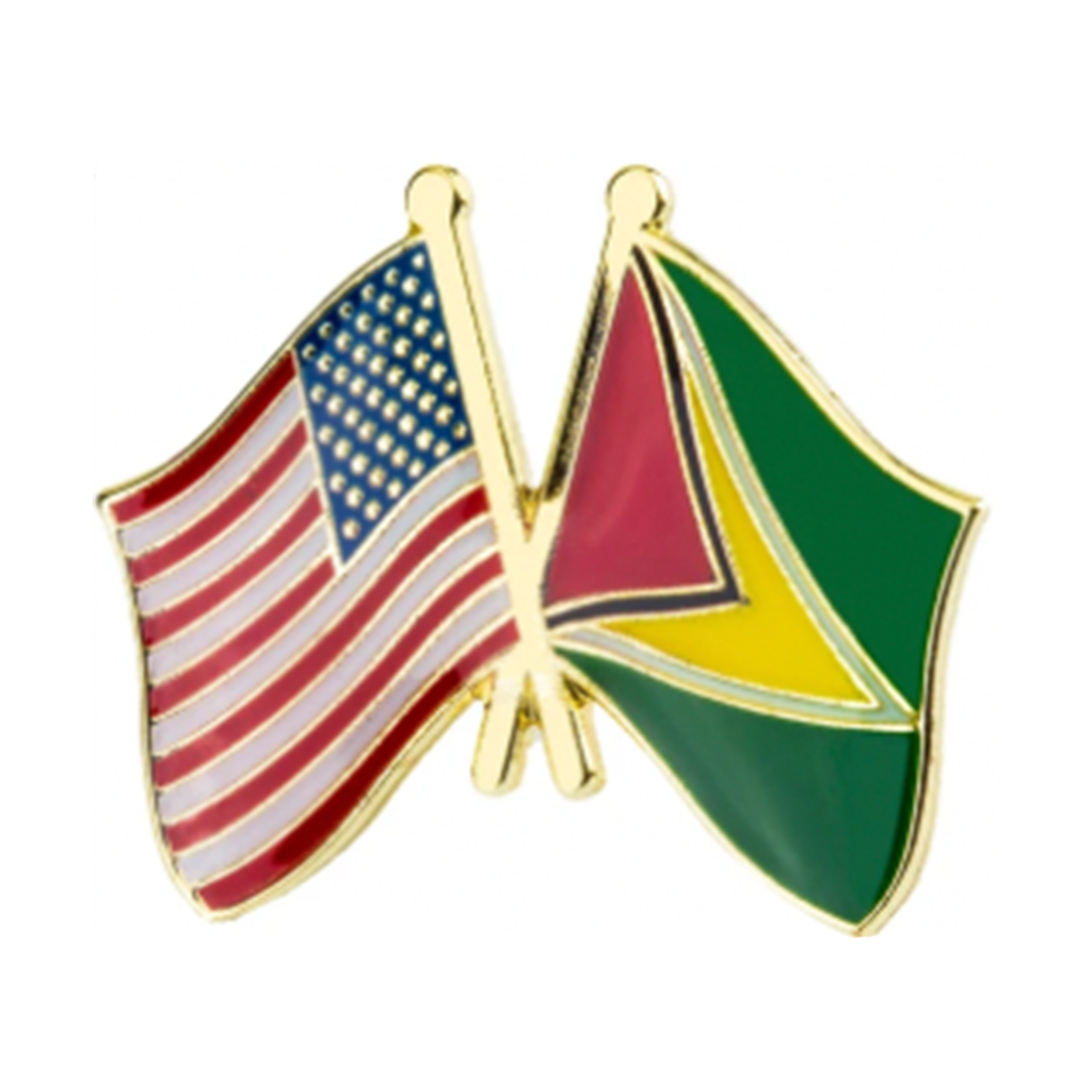 A friendship pin badge featuring enamel pins in the shape of the American and Guyanese flags, with a gold-colored metal backing.