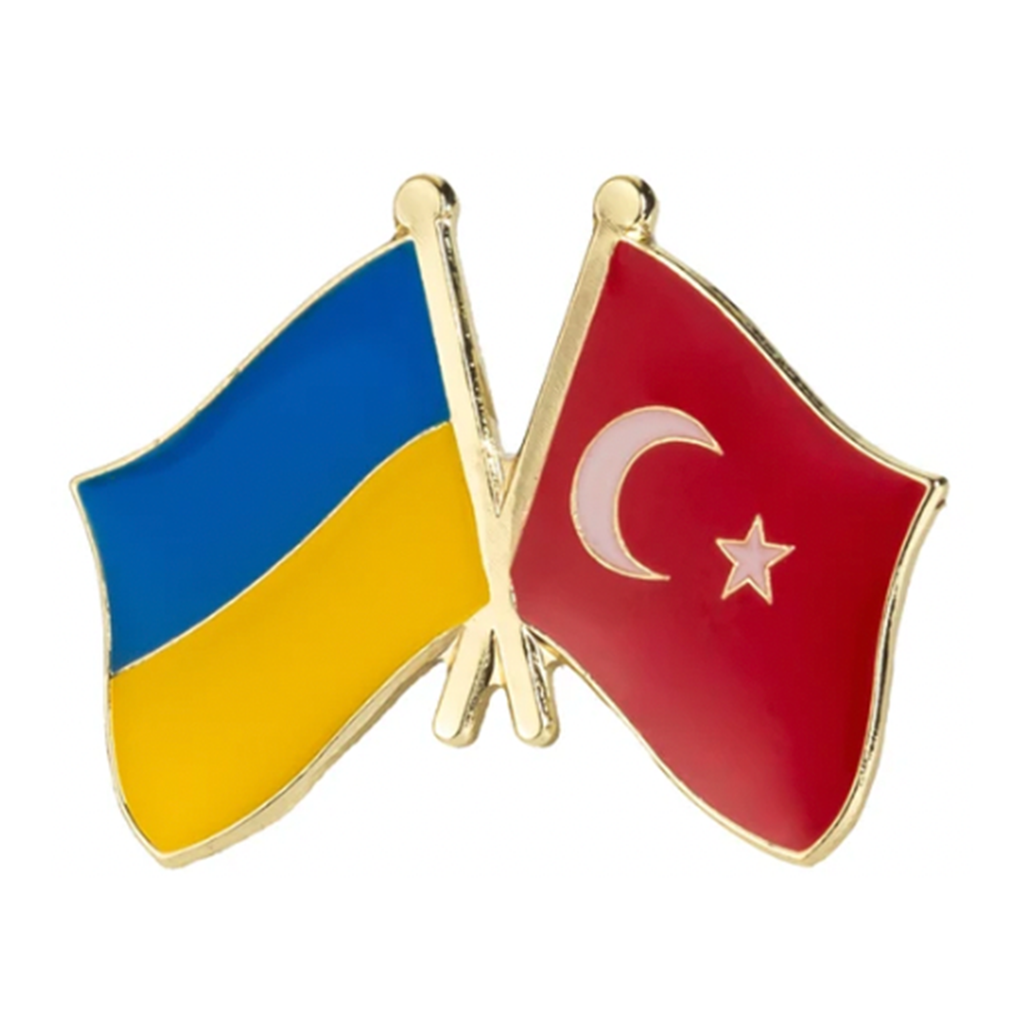 A pin badge featuring the flags of Ukraine and Turkey in a friendly design, with blue, yellow, red, and white colors.