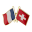 A pin badge featuring the French and Swiss flags, with a gold-colored metal badge and red and white enamel pins.