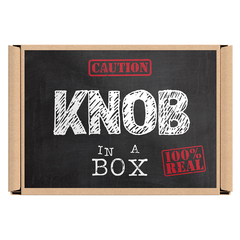 A cardboard box with the text 'KNOB IN A BOX' and a warning symbol indicating caution, alongside a mirrored surface showing the reflection of the person taking the picture. © Tigoli® 2026 All Rights Reserved Panda Loco Ltd  Imagen principal del producto