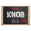 A cardboard box with the text 'KNOB IN A BOX' and a warning symbol indicating caution, alongside a mirrored surface showing the reflection of the person taking the picture. © Tigoli® 2026 All Rights Reserved Panda Loco Ltd 